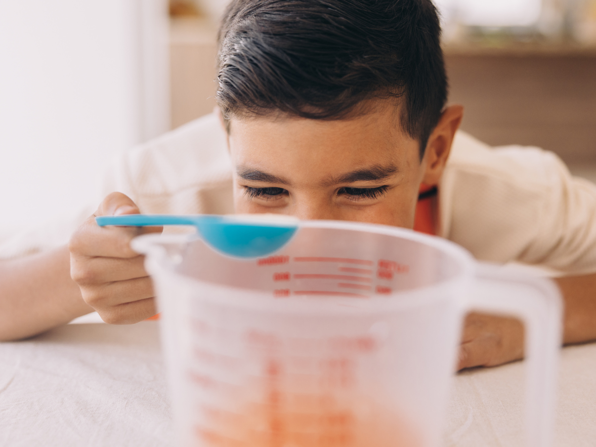 Child using measuring spoon to measure ingredients for baking